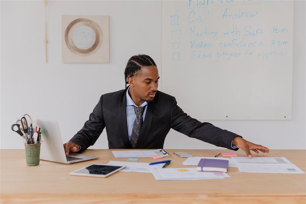 A businessman reviewing planning documents at his desk with a strategy whiteboard behind him