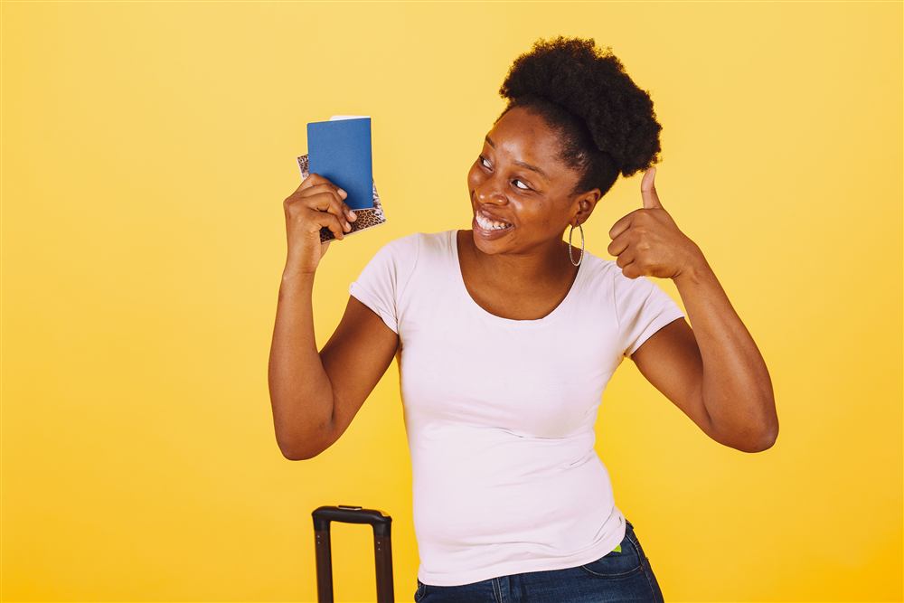 A woman smiling and holding her passport, excited and ready to travel
